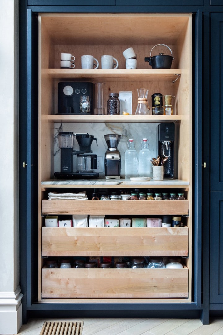 a built-in cabinet is used for a coffee station in a kitchen with pull out drawers for storage
