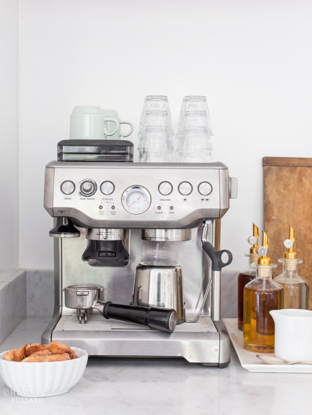 espresso machine on kitchen counter with coffee syrups on a white tray