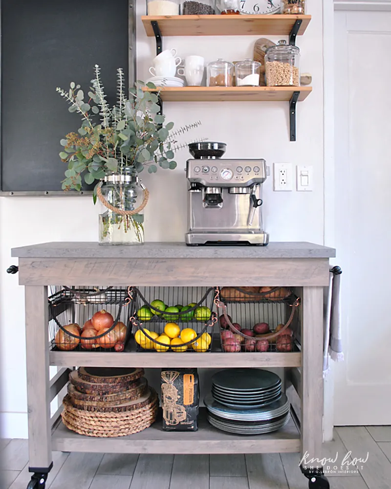 An industrial style wood bar cart on casters is used to house fruit in baskets and a coffee station