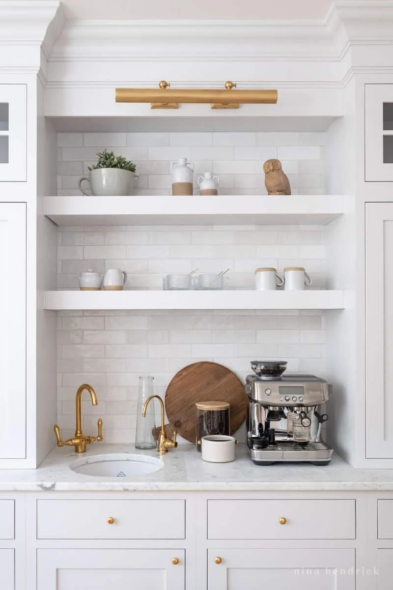 white floating shelving in a kitchen for storage for a coffee bar.