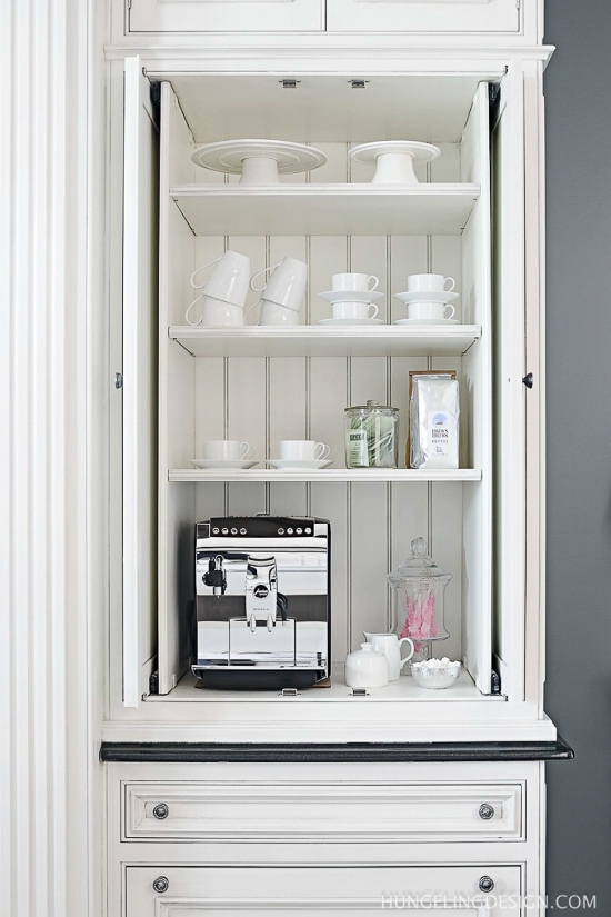 small hidden coffee machine with white coffee cups behind a closed cabinet