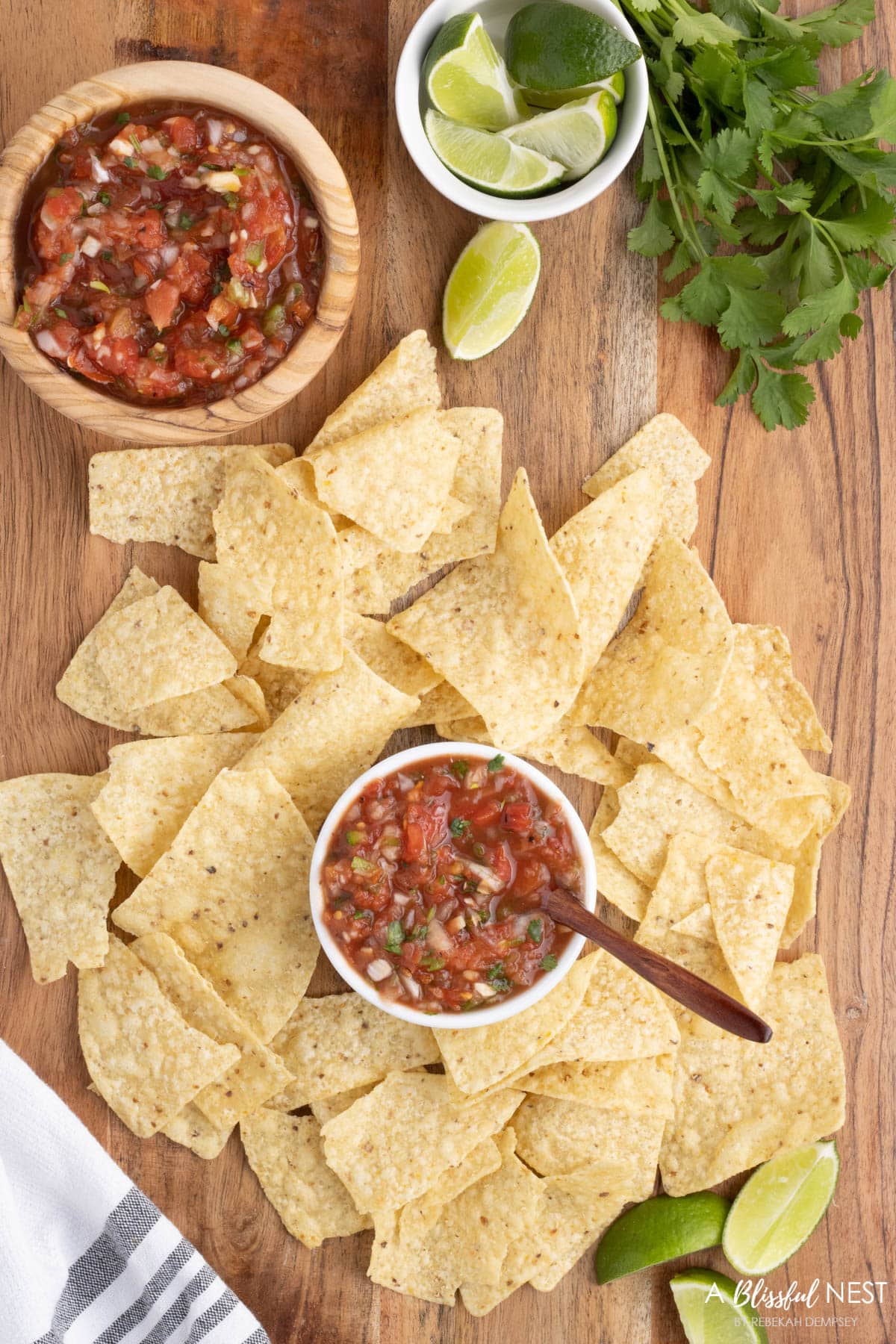 chips on a cutting board with a small bowl of salsa in the middle