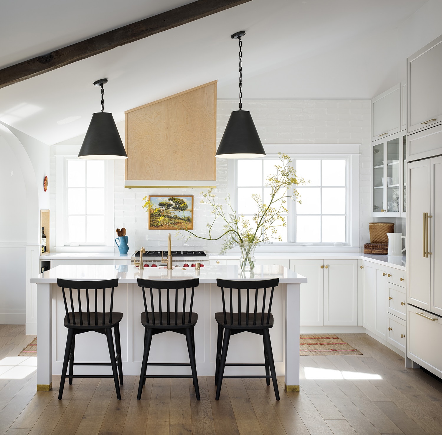 white kitchen with black barstools and black pendant lights