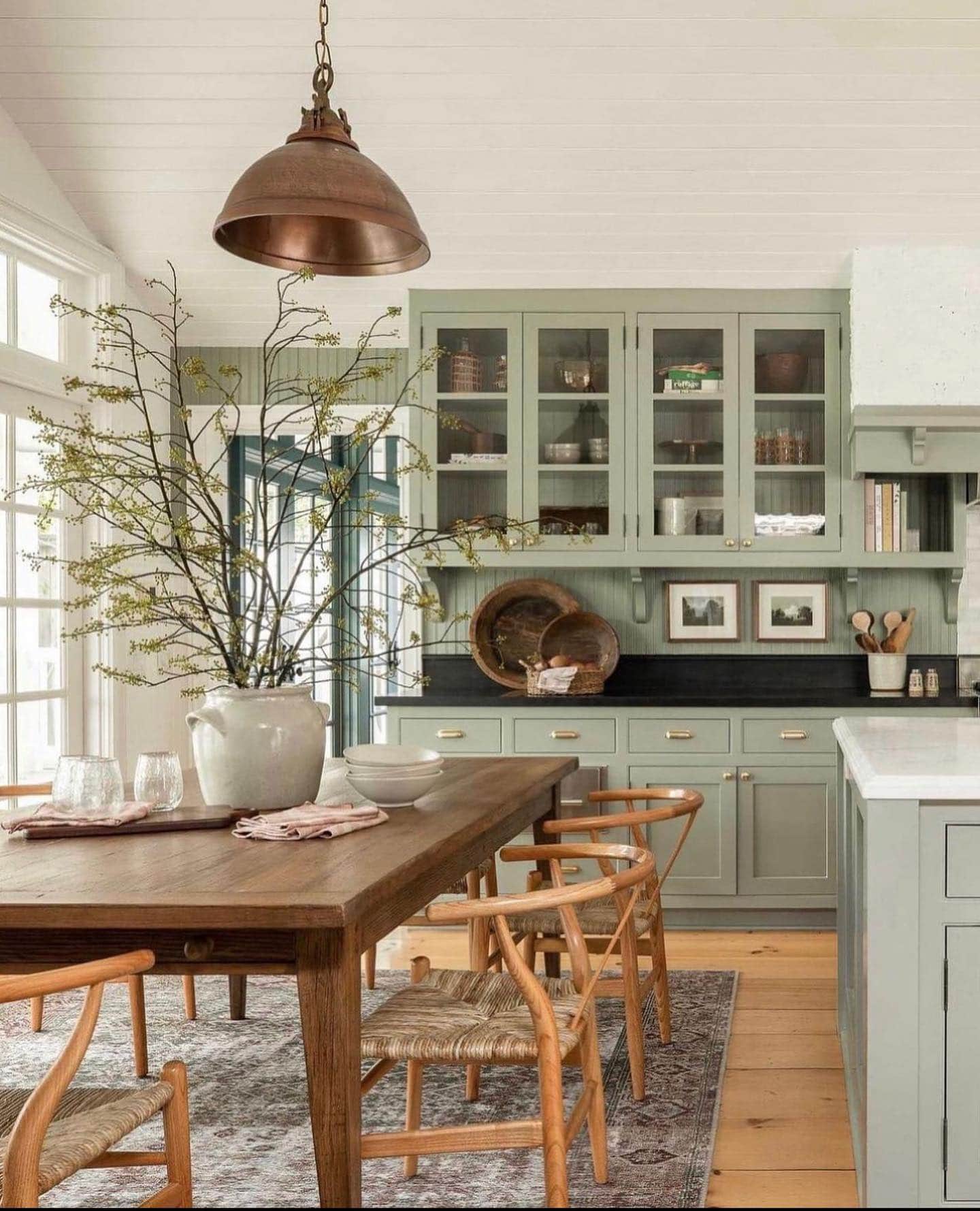 sage green kitchen cabinets with black countertops.