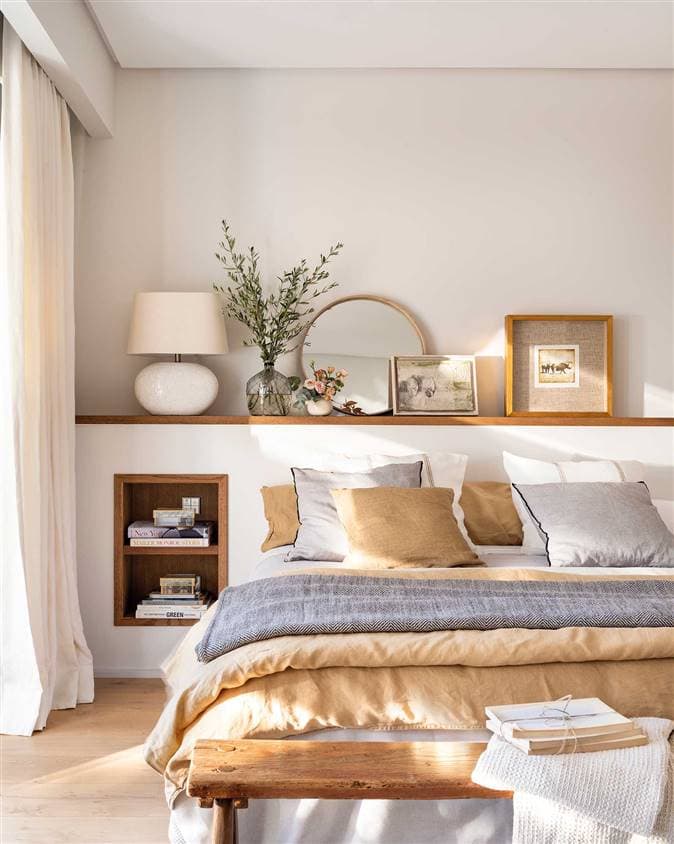 wood shelf behind a bed holding small art, mirror and a table lamp