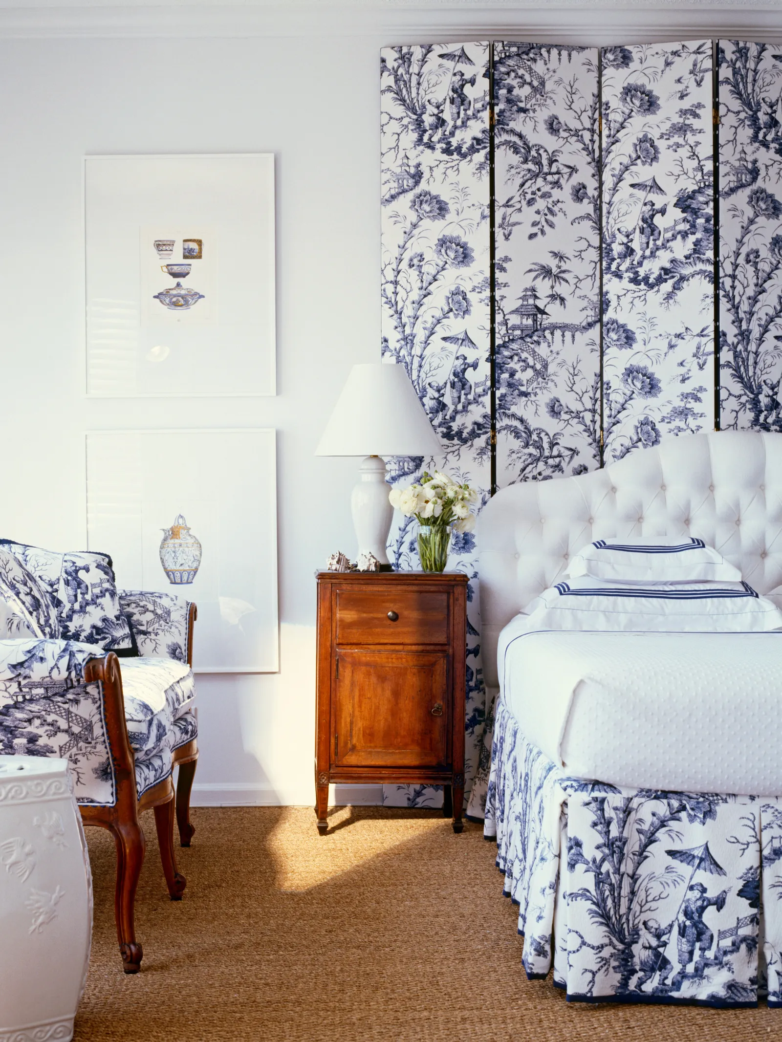 blue and white upholstered folding screen behind a bed