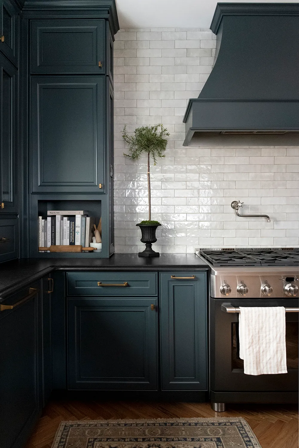dark teal kitchen cabinets with black counter top and gold cabinet hardware