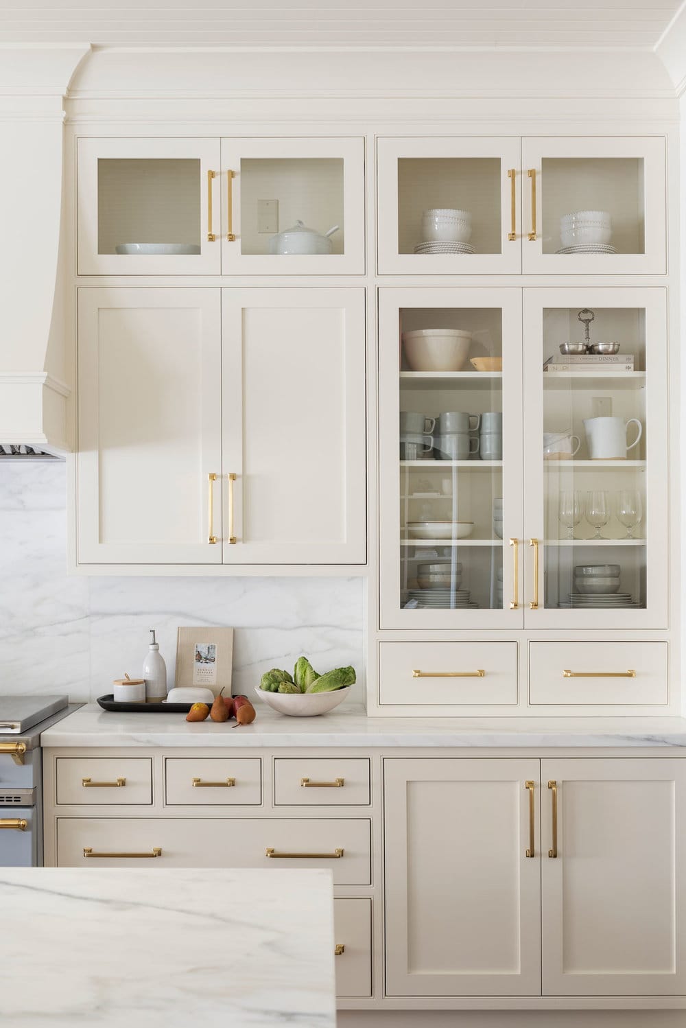 cream kitchen cabinets with white countertops and gold cabinet hardware