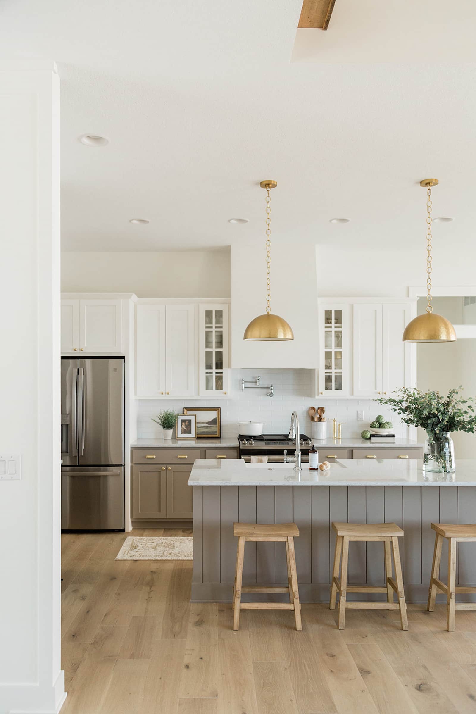 beige kitchen cabinets with white countertops and gold pendant lights