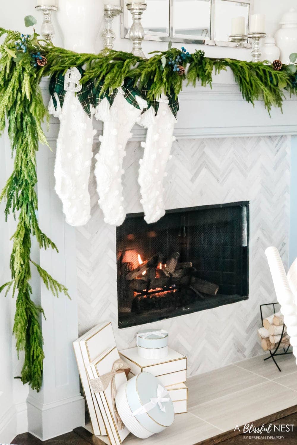 norfolk pine garland with chunky knit stockings on a fireplace mantel