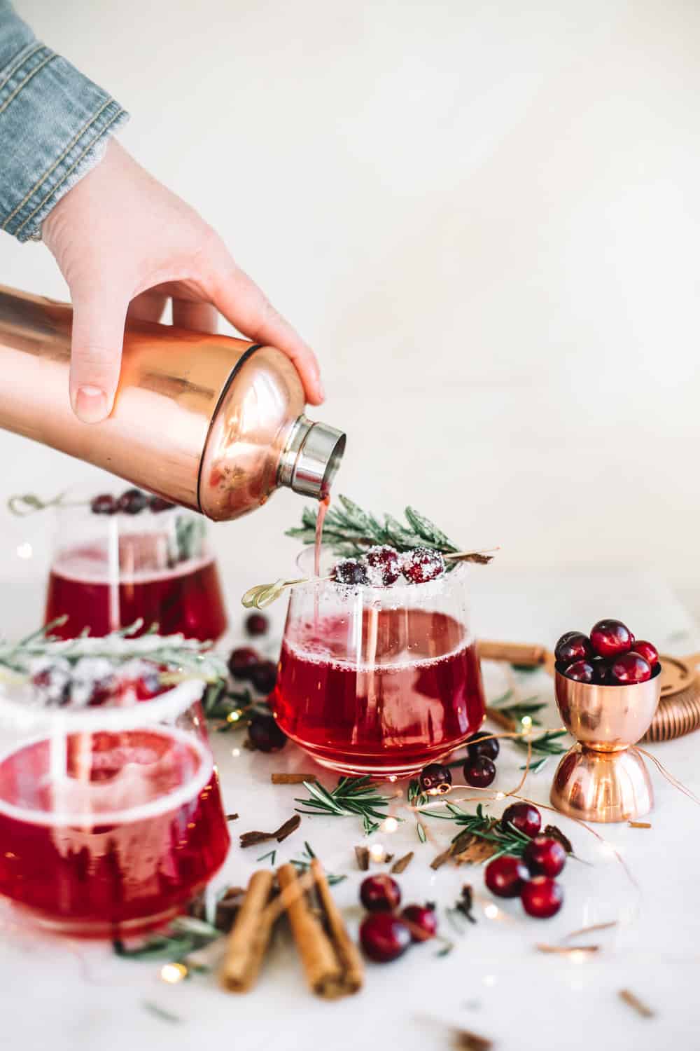 cocktail with sugared cranberries, cinnamon and rosemary sprig