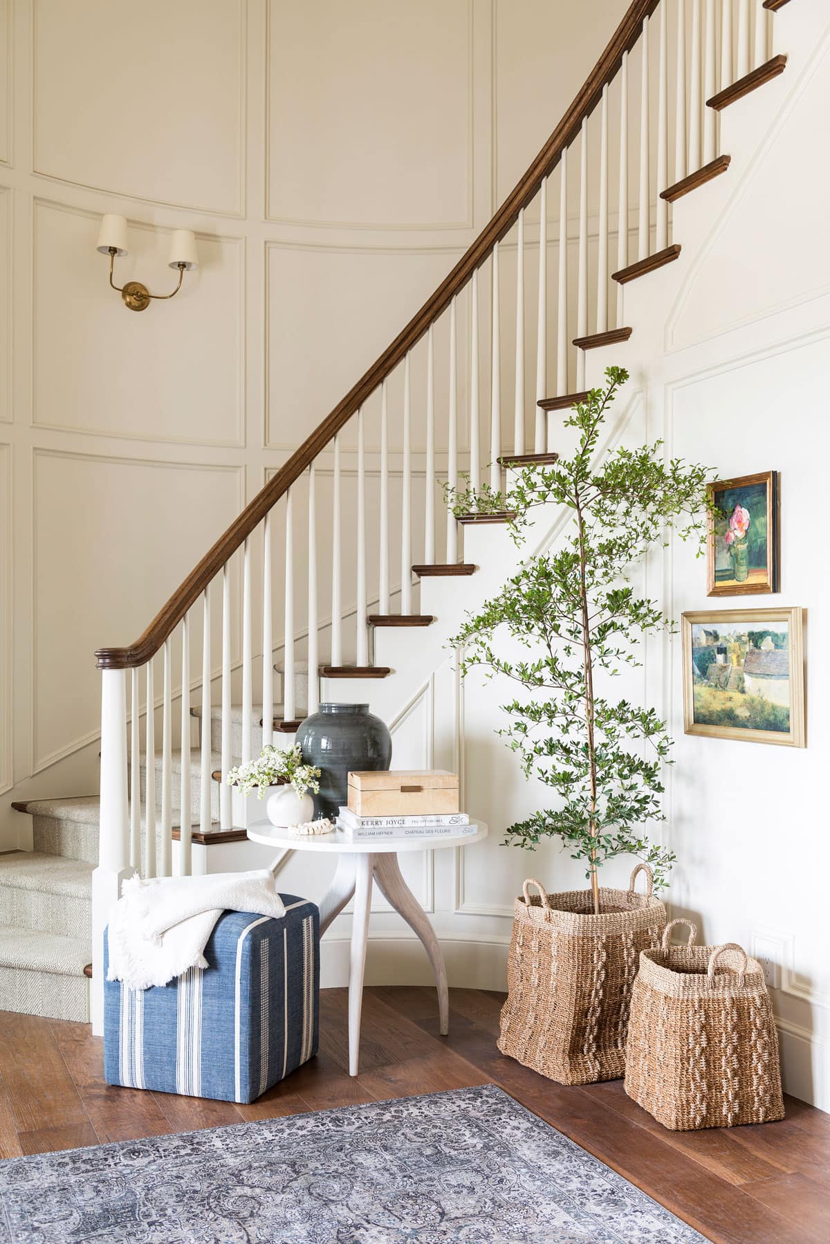 modern white table, blue and white ottoman, and a basket with a tree in an entryway