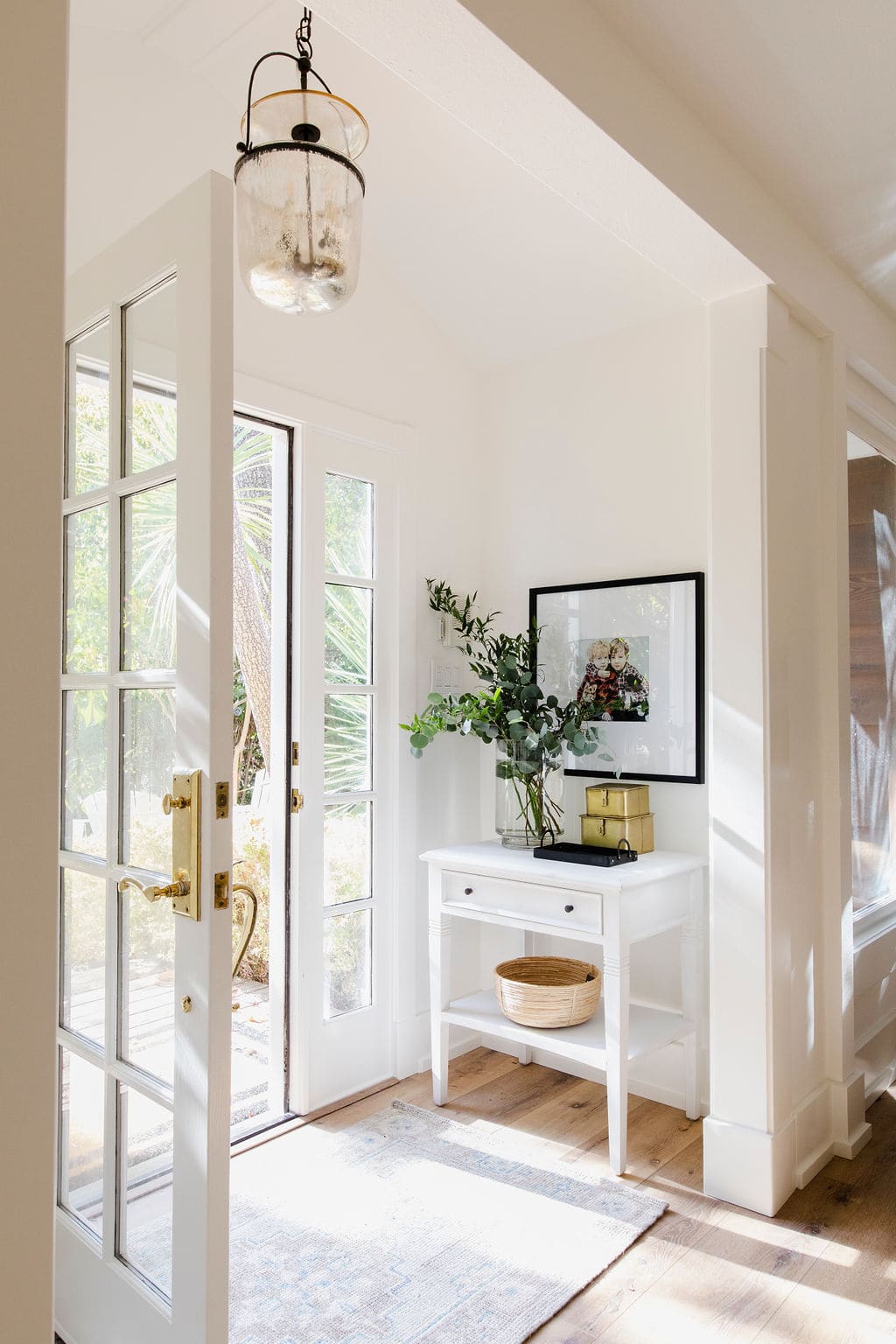 small entryway features a small white side table with a picture above