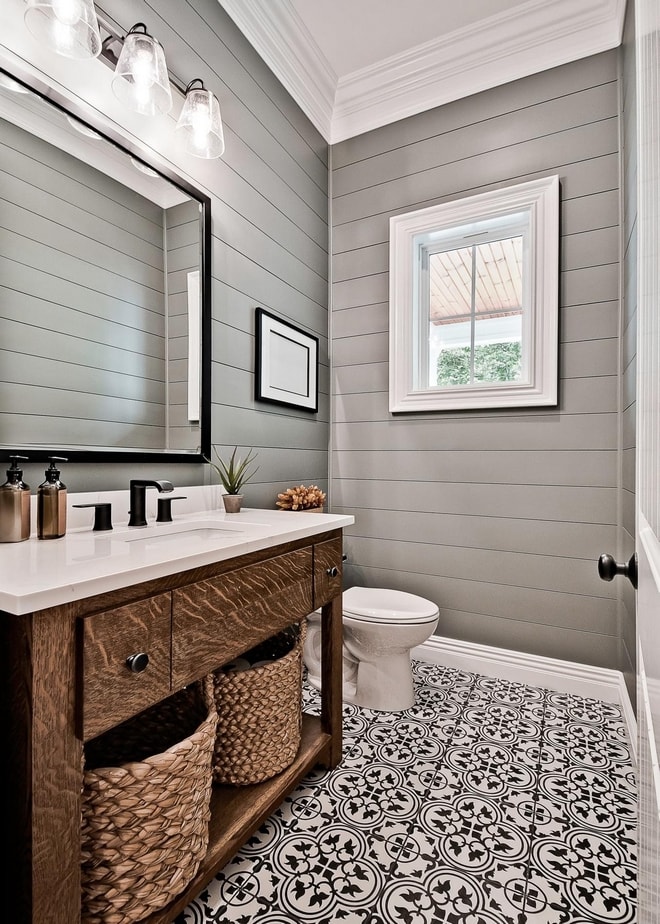 gray shiplap walls with black and white tile floor with a wood cabinet and black hardware