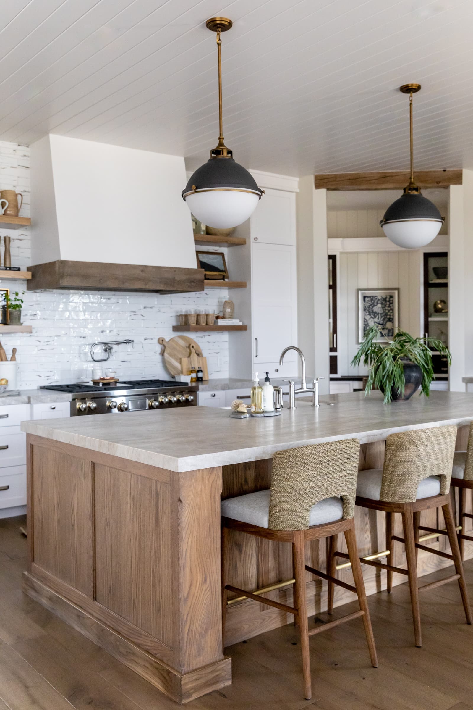 modern farmhouse kitchen with wood island, wood trim on hood, and round globe lights above the island