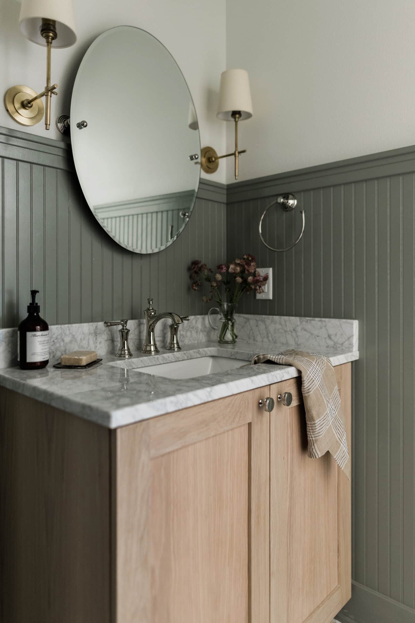 dark sage green beadboard and gold hardware with a wood vanity and marble countertop in this farmhouse powder room.