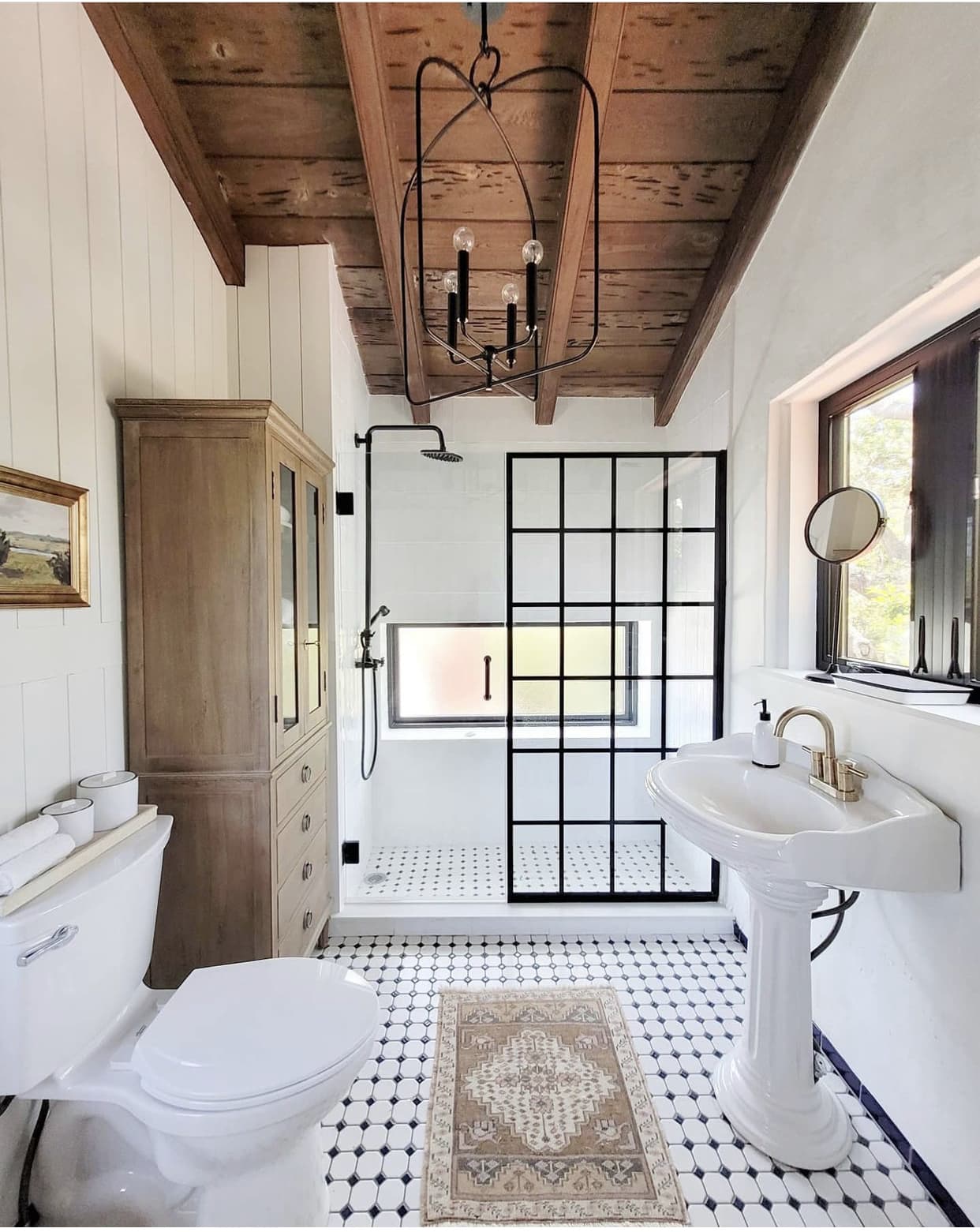 vintage pedestal sink with black and white patterned tile flooring in a rustic farmhouse bathroom.