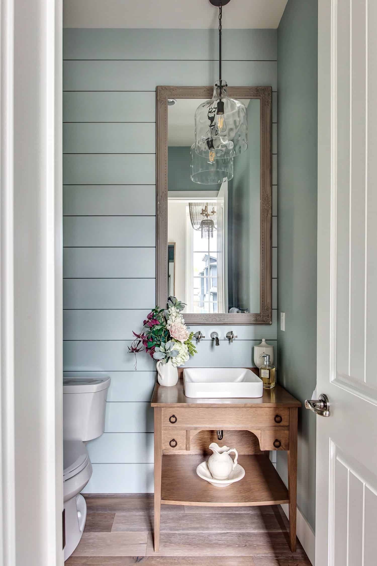 soft green shiplap walls, vintage cabinet turned into a bathroom vanity with a white raised sink on top.