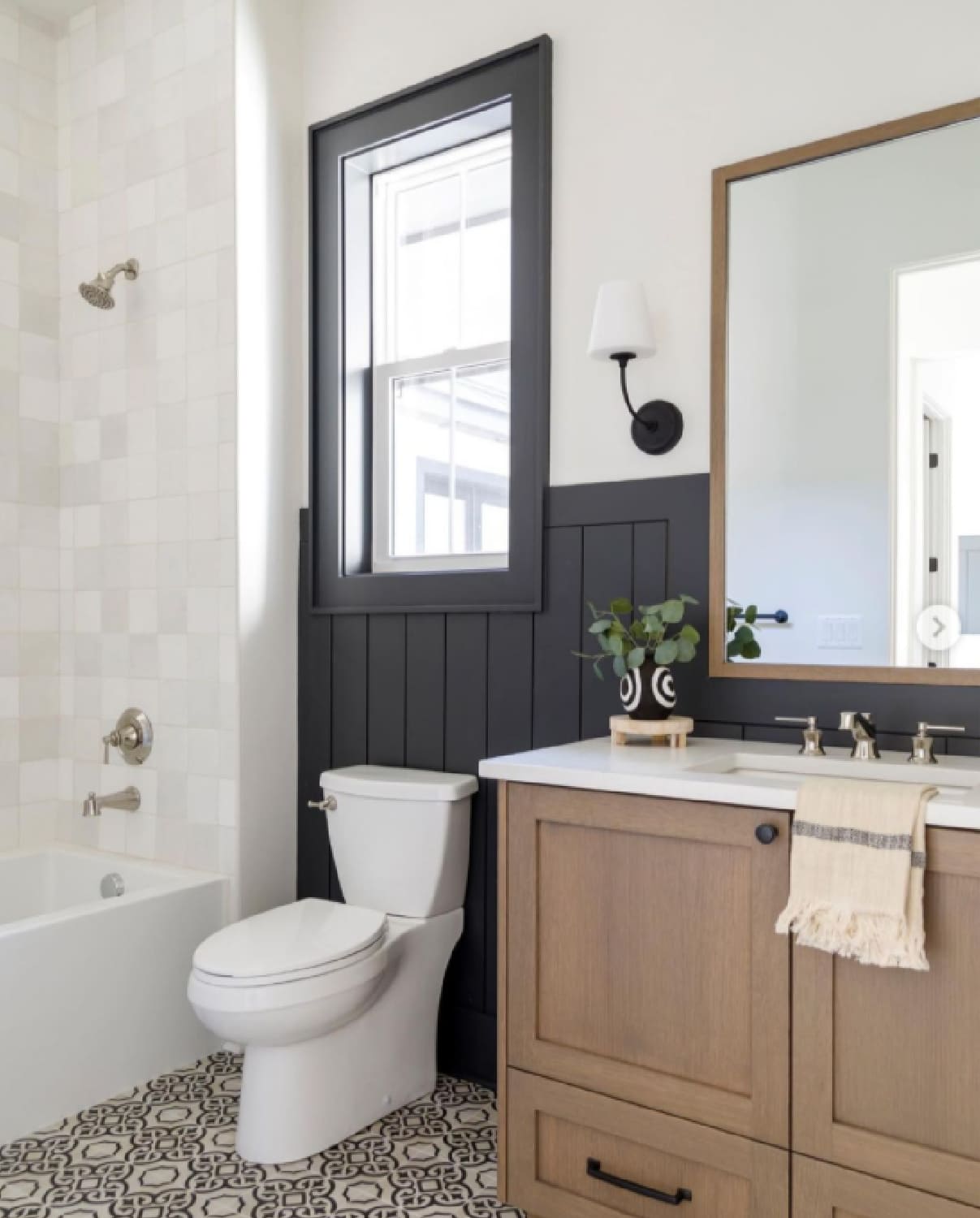 dark black vertical shiplap walls with black and white tiled floor in a small bathroom.