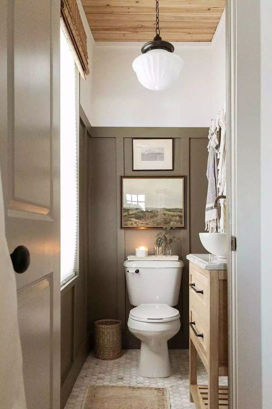 tall paneled walls painted a sage green in this farmhouse bathroom.