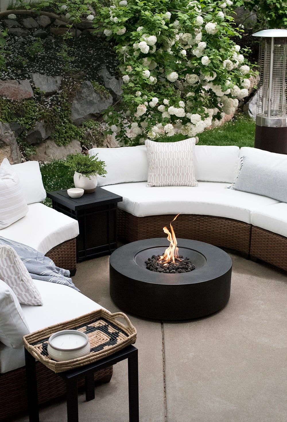 curved outdoor sofa with a black round fire pit int he middle