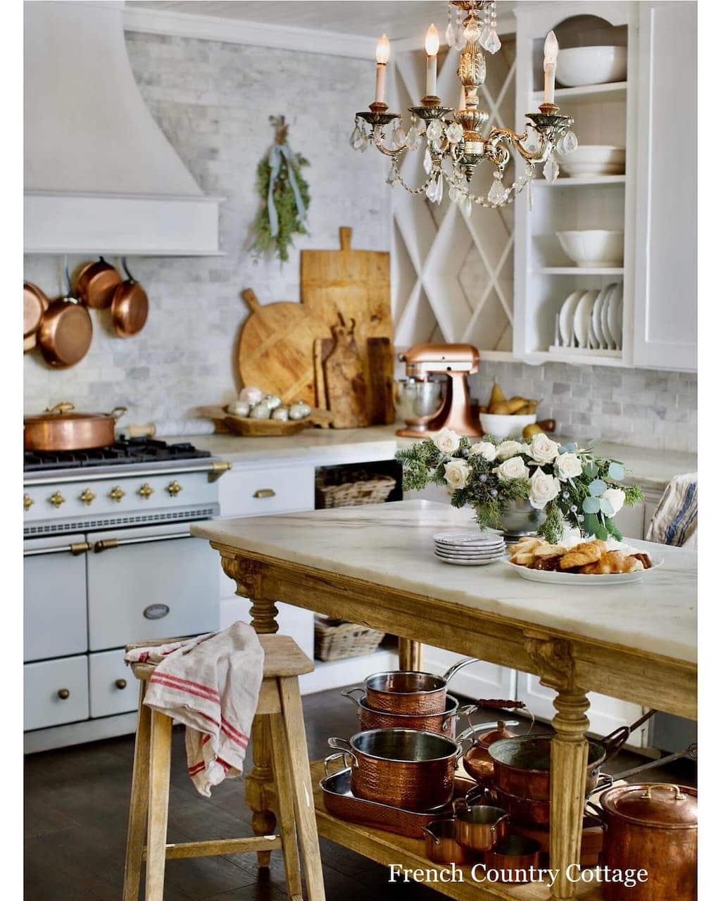 Antique table used as the kitchen island, collection of copper pots and wood cutting boards.