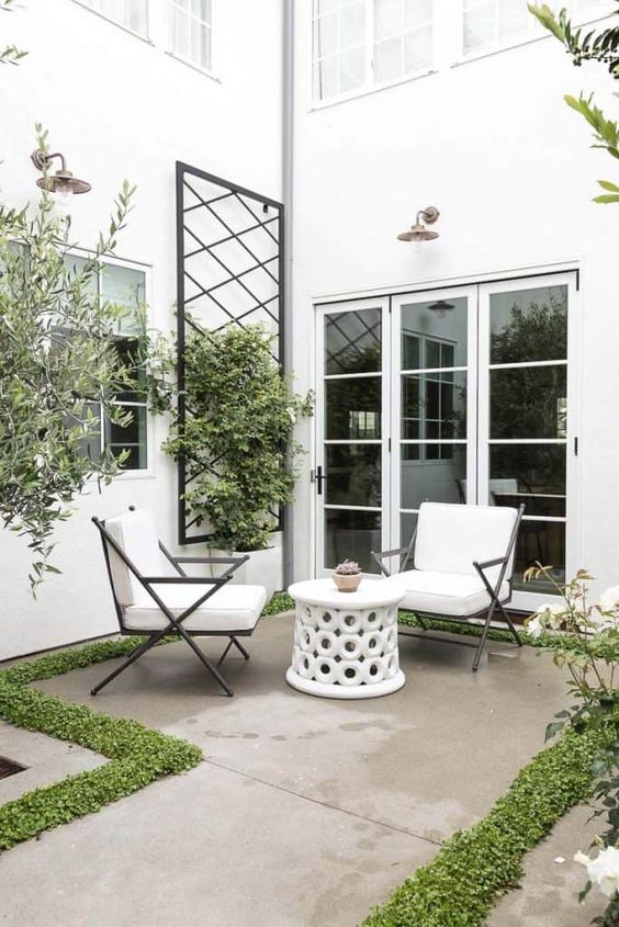 small seating area outside on a patio with vertical lattice for plants to grow on.