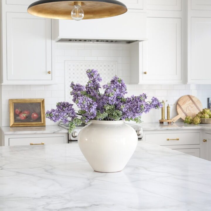 Image for Vibrant Purple Faux Flowers In A White Ceramic Vase