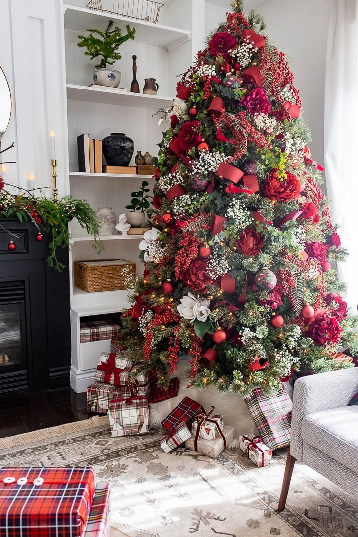 Create a cozy holiday moment with this classic Christmas tree, bursting with deep red flowers, berries, and lush greenery. Baby’s breath sprinkled throughout the branches looks just like tiny, delicate snowflakes, adding a dreamy winter feel. The bold red ribbon ties everything together and gives the whole tree a warm, inviting vibe. Add in plaid-wrapped presents below, and you have the perfect festive centerpiece that feels both timeless and welcoming. #elegantchristmastree #christmastreedecor #christmastreeideas