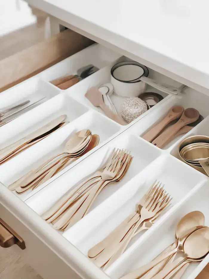 Drawer with organized gold and wooden cutlery, perfect for a cozy, elegant home.
